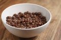 Chocolate cereal balls with milk in white bowl for breakfast on wooden table Royalty Free Stock Photo