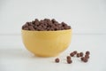 Chocolate cereal corn balls in a yellow bowl scattered on a white background. Copy, empty space for text Royalty Free Stock Photo