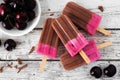 Chocolate and cherry ice pops. Overhead view table scene on rustic white wood. Royalty Free Stock Photo