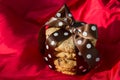 Chocolate chip cookie with brown silk bow and white dots on a red silk background Royalty Free Stock Photo