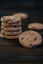 Chocolate chip cookies on dark background with glass of milk