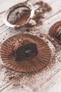 Chocolate chip muffin in brown wax paper. Unwrapped. Cocoa powder in the background Royalty Free Stock Photo