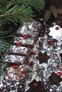 Chocolate Christmas log in powdered sugar with cranberries. Christmas tree branches