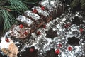 Chocolate Christmas log in powdered sugar with cranberries. Christmas tree branches