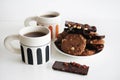 Chocolate cookies with chocolate slices and nuts on a plate next to two cups of tea Royalty Free Stock Photo