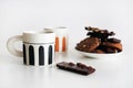 Chocolate cookies with chocolate slices and nuts on a plate next to two cups of tea Royalty Free Stock Photo