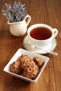 Chocolate cookies with walnuts and raisins in a square bowl and a cup of black tea on a wooden table. Royalty Free Stock Photo