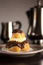 Chocolate cream puff pastry with a silver set of coffee and milk Royalty Free Stock Photo