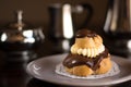 Chocolate cream puff pastry with a silver set of coffee and milk Royalty Free Stock Photo