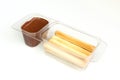 Chocolate cream in transparent plastic container. Sweet wafer sticks and brown hazelnut cream isolated on white