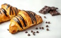 Chocolate croissant with chocolate pieces on white background