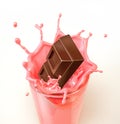 Chocolate cubes splashing into a glass full of strawberry milkshake. Royalty Free Stock Photo