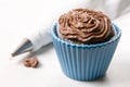 Chocolate cup cake with ganache chocolate cream and piping bag in the background on the white marble background Royalty Free Stock Photo