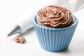 Chocolate cup cake with ganache chocolate cream and piping bag in the background on the white marble background Royalty Free Stock Photo