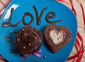 Chocolate cupcake with chocolate cream and chocolate cupcake in the form of a heart on a blue plate with the inscription love.