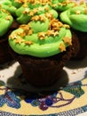 Chocolate cupcake with green frosting and golden stars sprinkles on a white mosaic-patterned plate