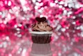 Chocolate cupcake with icing and chocolate heart sparkly pink party background