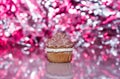 Chocolate cupcake with icing and sparkly pink party background