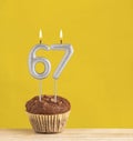 Chocolate cupcake with number 67 candle - Birthday on a yellow background Royalty Free Stock Photo