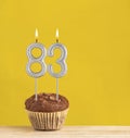 Chocolate cupcake with number 83 candle - Birthday on a yellow background Royalty Free Stock Photo