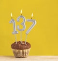 Chocolate cupcake with number 137 candle - Birthday on a yellow background Royalty Free Stock Photo