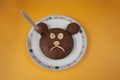 Chocolate cupcakes in the shape of a bear with banana on a plate on orange background. Bear has sad expression on its face because Royalty Free Stock Photo
