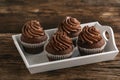 Chocolate cupcakes with chocolate swirl icing on tray on wooden table. Homemade muffins