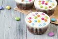 Chocolate cupcakes with white icing and colored smarties, wooden background Royalty Free Stock Photo