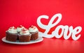 4 chocolate cupcakes with white LOVE sign on a red background