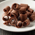 Chocolate curls on a white plate, displayed against a dark surface. The spirals range in size, Royalty Free Stock Photo