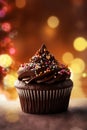 Chocolate dark muffin close-up on blurred beautiful shining background with festive yellow lights. Brown sprinkled cupcake on Royalty Free Stock Photo