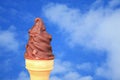 Chocolate Dipped Soft Serve Ice Cream Cone Against Vivid Blue Sky with White Cloud Royalty Free Stock Photo