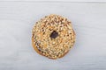 Chocolate donut sprinkled with nuts on white wooden background