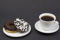 Chocolate donuts and coffee. Two beautiful tasty donuts on a saucer and a cup of aromatic hot coffee