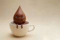 A chocolate drop with a face sitting in a cup. Space for text. Royalty Free Stock Photo