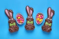 Chocolate Easter Bunnies, Halves Of Egg With Candies On Light Blue Background, Flat Lay