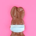 Chocolate Easter bunny wearing a medical face mask for protection to the coronavirus