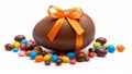 Chocolate Easter egg with orange ribbon and colorful candy on white background Royalty Free Stock Photo