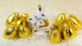 Chocolate Easter eggs in bright golden cover around the porcelain rabbit