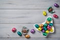 Chocolate Easter eggs wrapped in colorful foil in a butterfly shaped bowl on a wooden background, top view, copy space Royalty Free Stock Photo