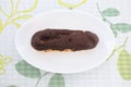 Chocolate eclair cream puff on plate on table Royalty Free Stock Photo