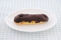 Chocolate eclair cream puff on plate on table Royalty Free Stock Photo