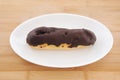 Chocolate eclair cream puff on plate on table Royalty Free Stock Photo