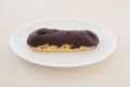 Chocolate eclair cream puff on plate on table Royalty Free Stock Photo