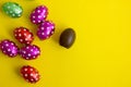 Chocolate egg in colorful foil for Easter on yellow background. The egg is wrapped in red foil. Happy Easter. Chocolate. Sweets Royalty Free Stock Photo