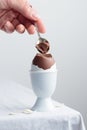 Chocolate eggs on white eggstand holder with a hand Royalty Free Stock Photo