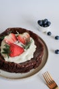 Chocolate flourless cake with strawberries, blueberries and whipping cream. Royalty Free Stock Photo