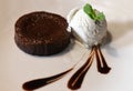 A chocolate fondant cake with a ball of vanilla ice cream on a white plate decorated with liquid chocolate Royalty Free Stock Photo