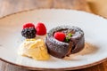 Chocolate fondant cupcake with raspberries, ice creme and powdered sugar placed on plate Royalty Free Stock Photo