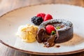 Chocolate fondant cupcake with raspberries, ice creme and powdered sugar placed on plate Royalty Free Stock Photo